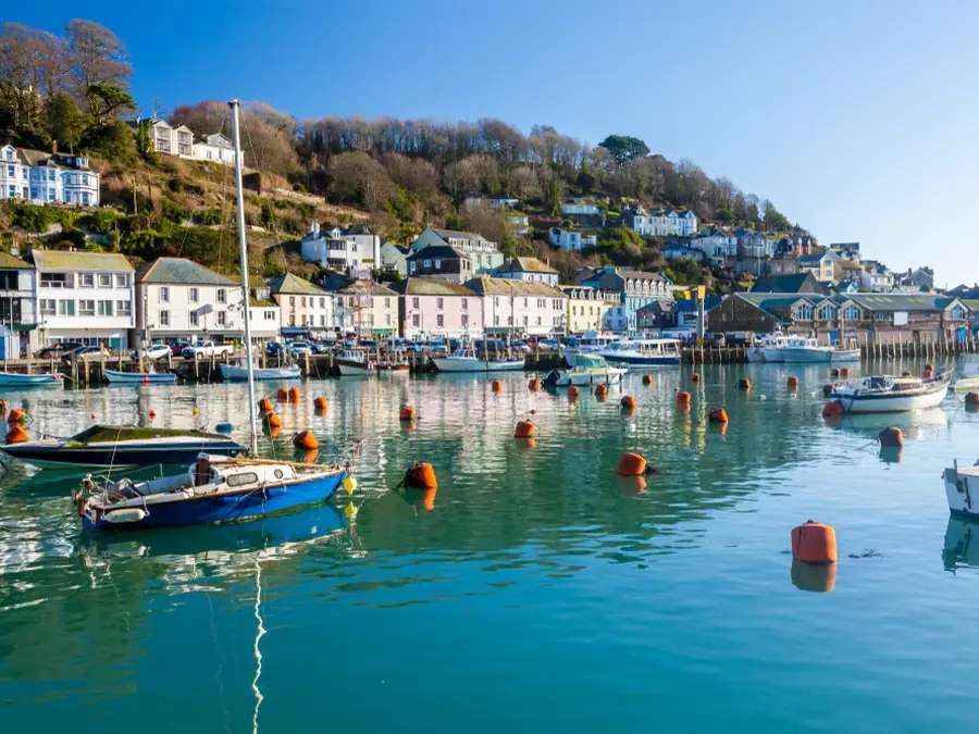 Fishing boats in Looe harbour with painted houses above the waterfront, Cornwall